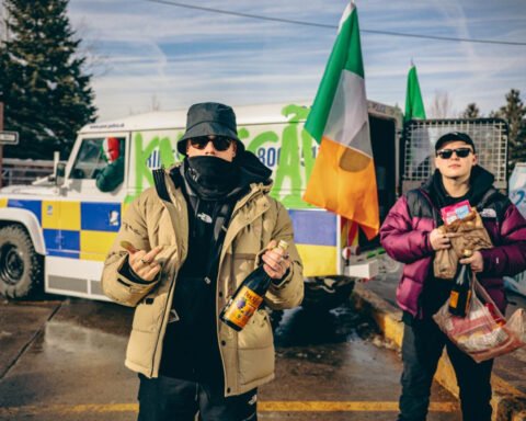 Irish-language hip-hop trio KNEECAP in front of a police car