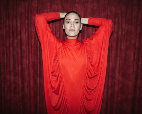 Nadine Shah promotional shot in front of red curtain