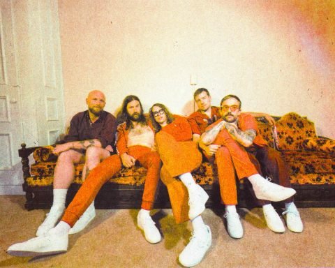 IDLES on orange sofa. Promotional image for 'pop pop pop'