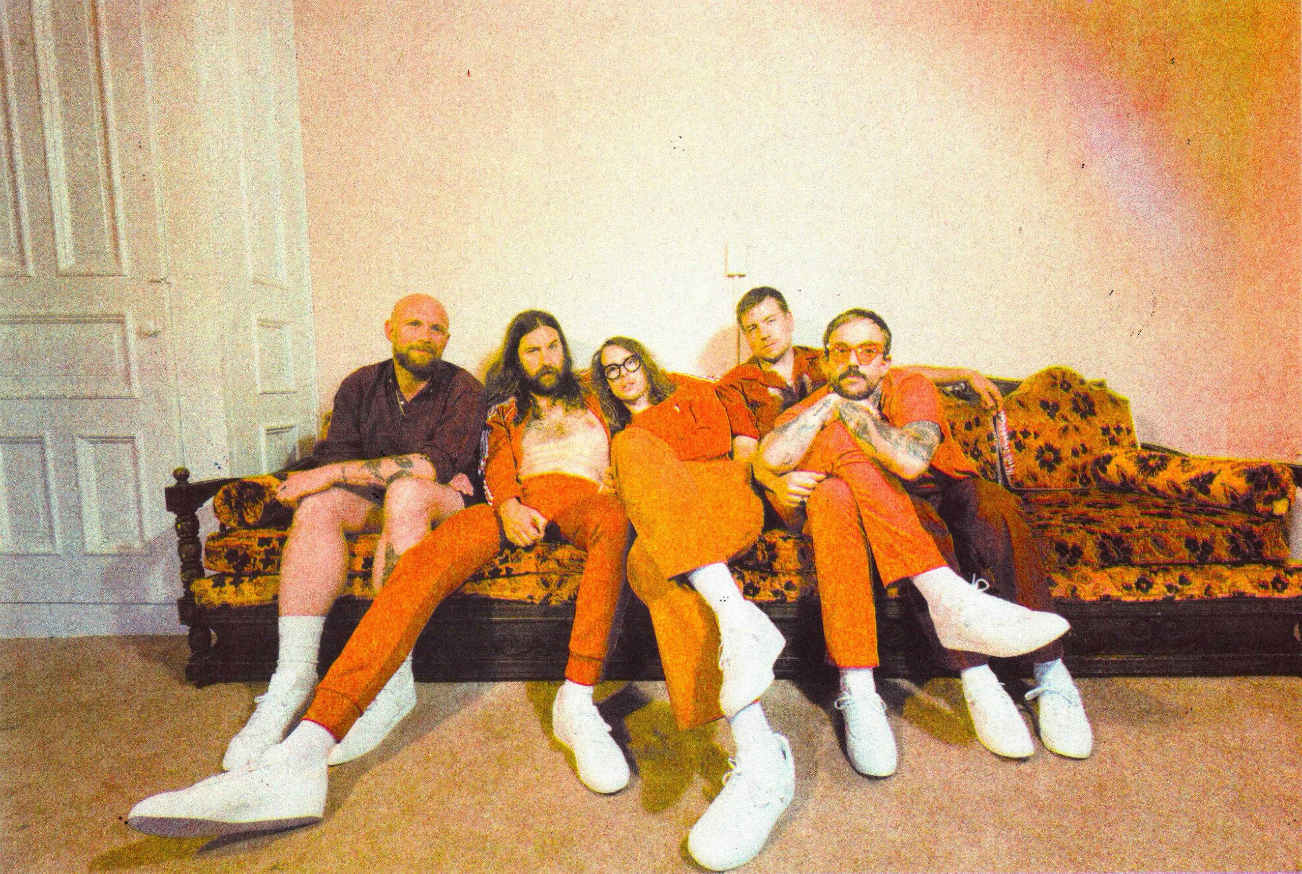 IDLES on orange sofa. Promotional image for 'pop pop pop'