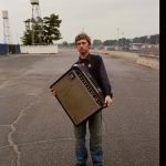 songwriter Greg Freeman holding an amplifier