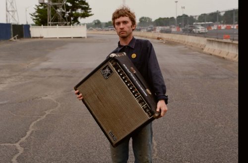 songwriter Greg Freeman holding an amplifier